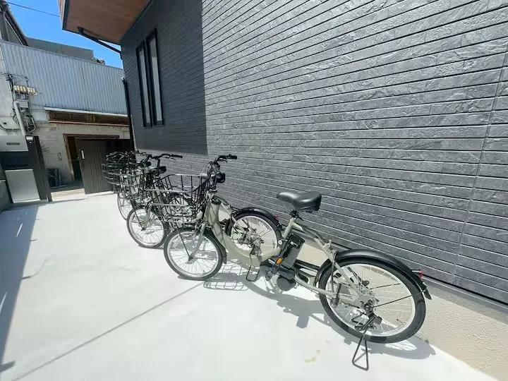 建物の外壁沿いに複数の自転車を並べた屋外スペース